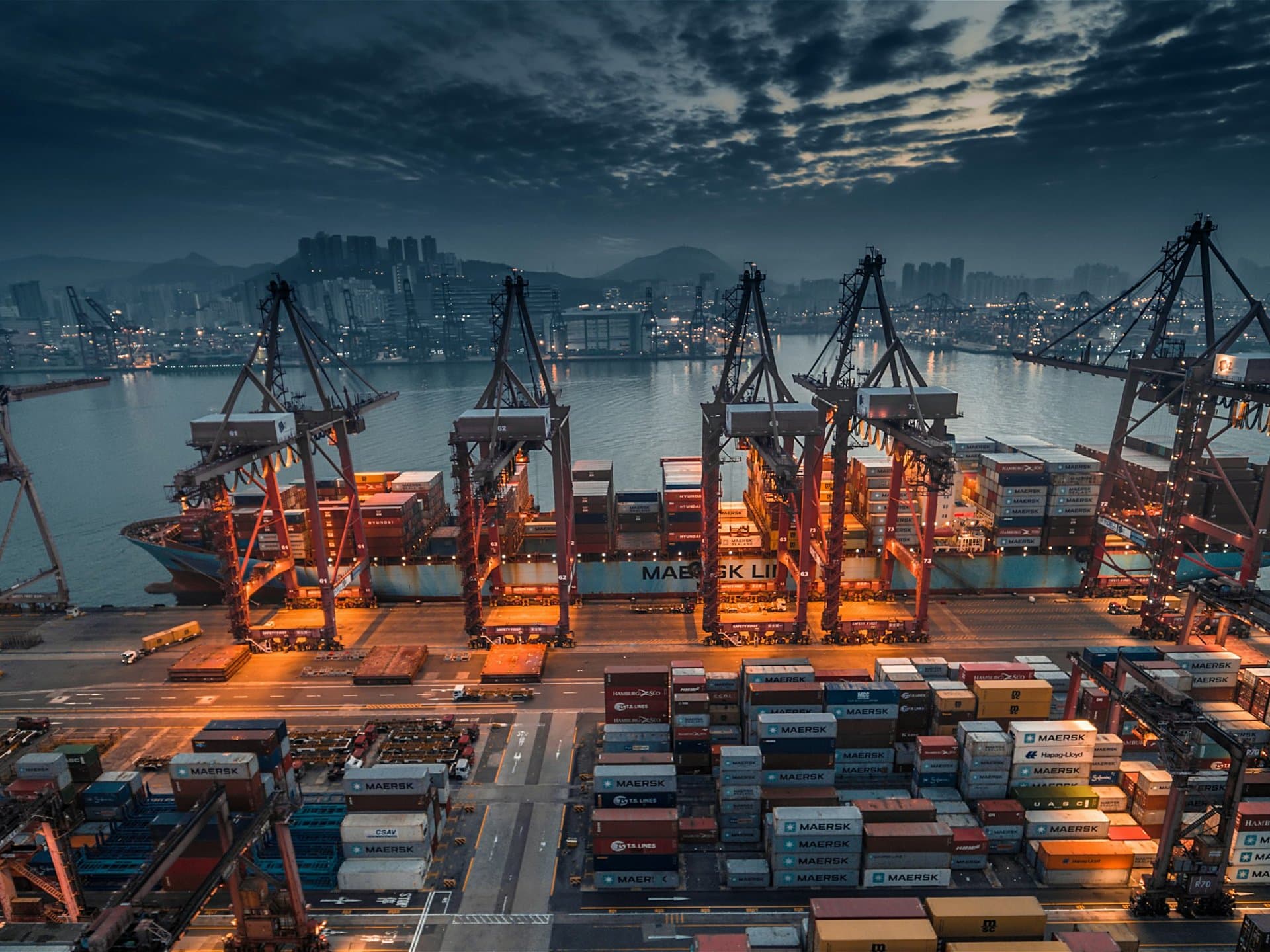 Cranes loading a container ship at dusk